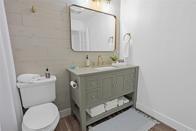 bathroom featuring toilet, wood finished floors, vanity, and baseboards