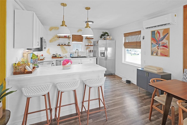 kitchen featuring a peninsula, appliances with stainless steel finishes, a wall mounted AC, and light countertops