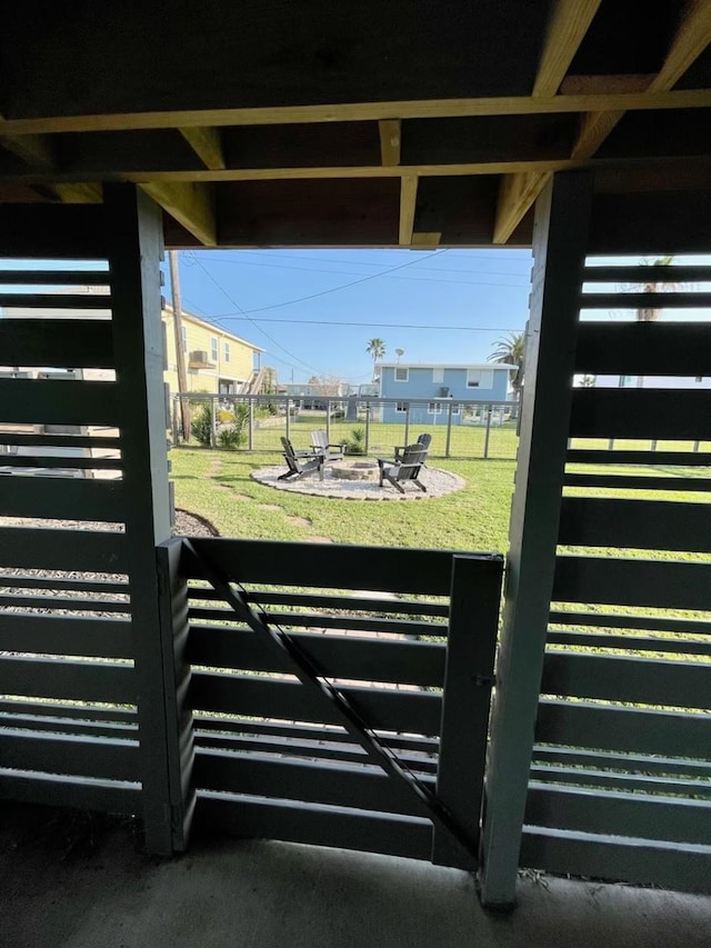 view of gate with a fire pit, a yard, and fence