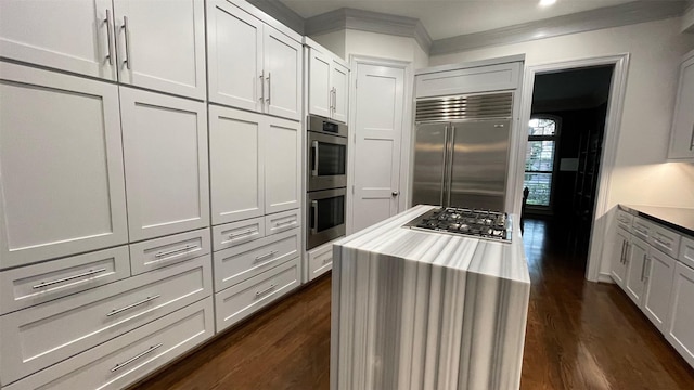 kitchen with ornamental molding, light countertops, appliances with stainless steel finishes, and dark wood-type flooring