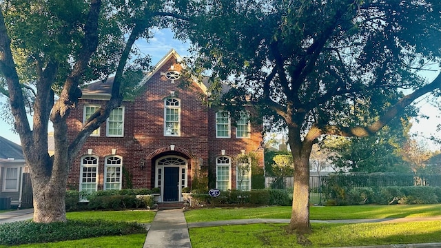 view of front of home featuring central AC unit, a front lawn, and brick siding