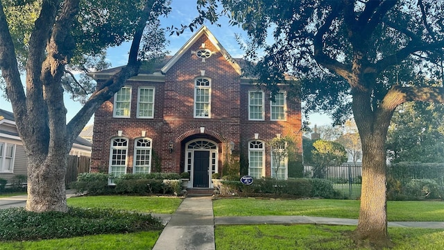 view of front of home with a front yard, fence, and brick siding