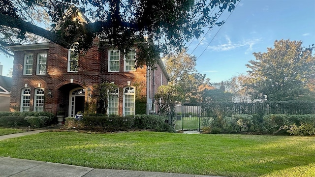 view of front of property with brick siding, a front yard, and fence