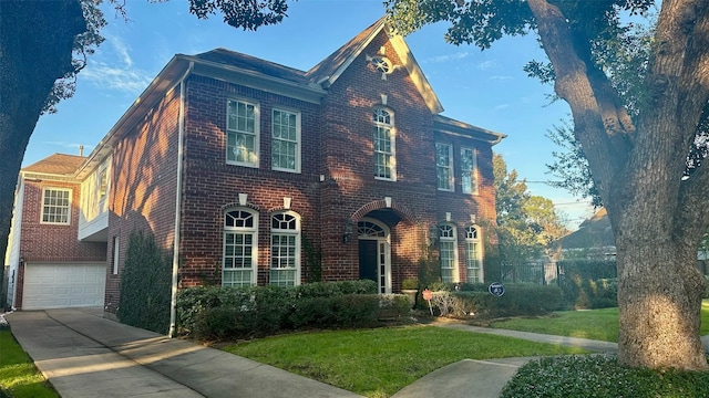 view of front of house featuring driveway, an attached garage, a front lawn, and brick siding