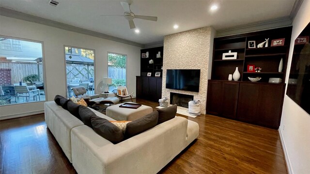 living area featuring recessed lighting, a large fireplace, wood finished floors, a ceiling fan, and ornamental molding