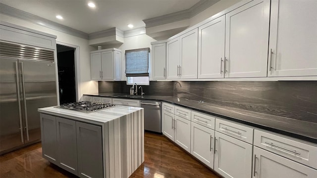 kitchen featuring a center island, dark wood finished floors, stainless steel appliances, backsplash, and a sink