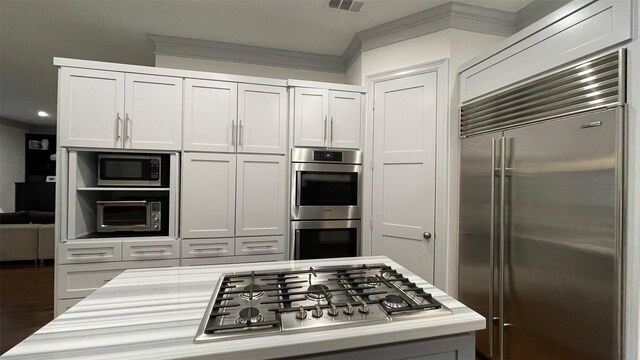 kitchen with visible vents, dark wood-style flooring, built in appliances, light countertops, and crown molding