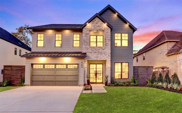 view of front of house featuring driveway, an attached garage, a standing seam roof, a yard, and brick siding