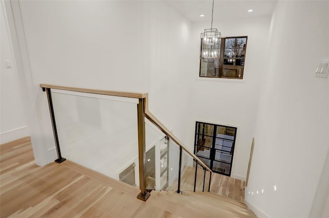 staircase featuring a notable chandelier, baseboards, wood finished floors, and recessed lighting