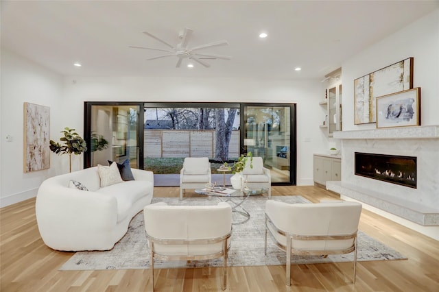 living room featuring recessed lighting, baseboards, wood finished floors, and a high end fireplace