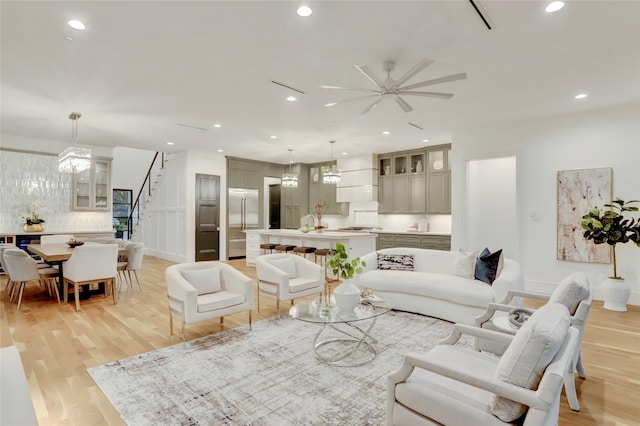 living room featuring recessed lighting, ceiling fan, stairway, and light wood finished floors