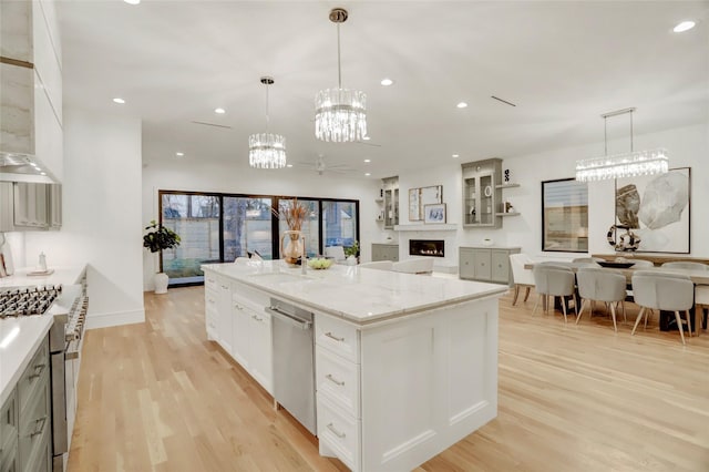 kitchen with recessed lighting, light wood-style flooring, appliances with stainless steel finishes, open floor plan, and a lit fireplace