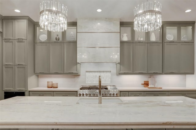 kitchen featuring hanging light fixtures, gray cabinets, backsplash, and a notable chandelier