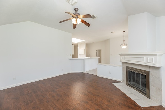 unfurnished living room featuring baseboards, a tiled fireplace, visible vents, and light wood-style floors