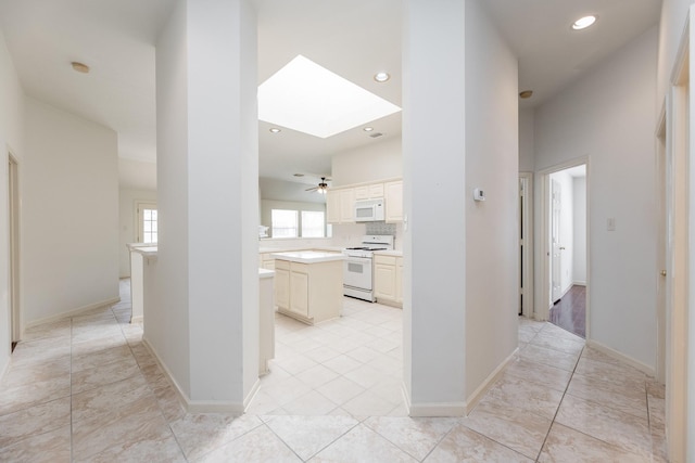 hallway with light tile patterned floors, recessed lighting, a skylight, and baseboards