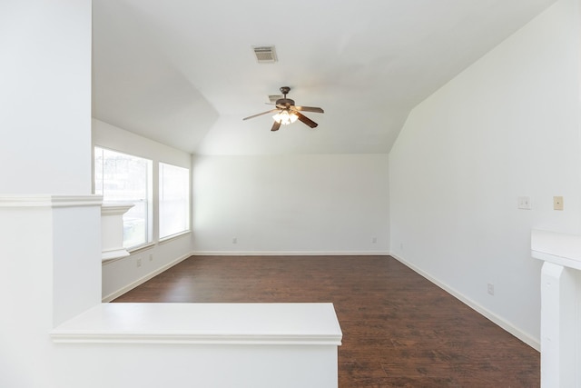 spare room with vaulted ceiling, visible vents, dark wood finished floors, and baseboards