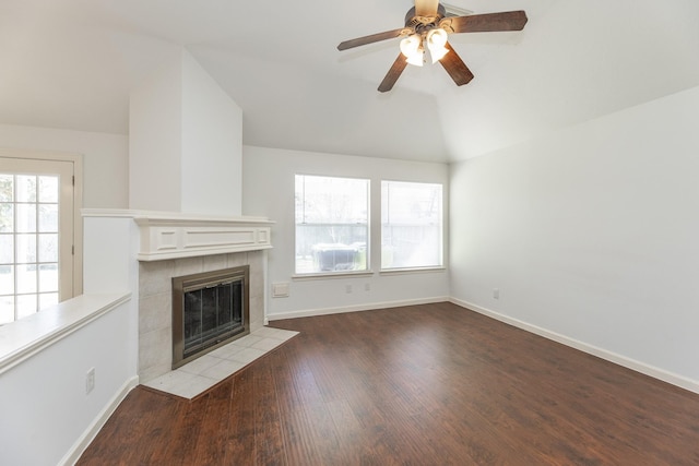 unfurnished living room with lofted ceiling, wood finished floors, a ceiling fan, baseboards, and a tiled fireplace