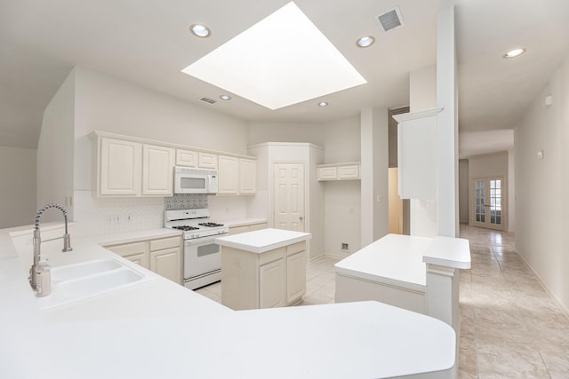 kitchen featuring a peninsula, white appliances, a kitchen island, a sink, and tasteful backsplash