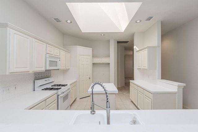 kitchen with a skylight, light tile patterned floors, visible vents, decorative backsplash, and white appliances