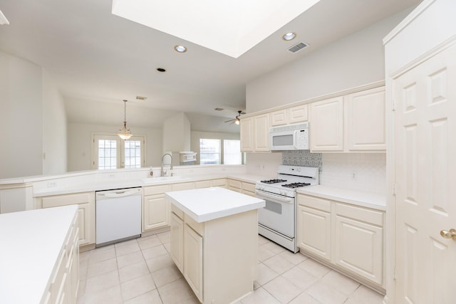 kitchen with white appliances, tasteful backsplash, visible vents, a peninsula, and a sink