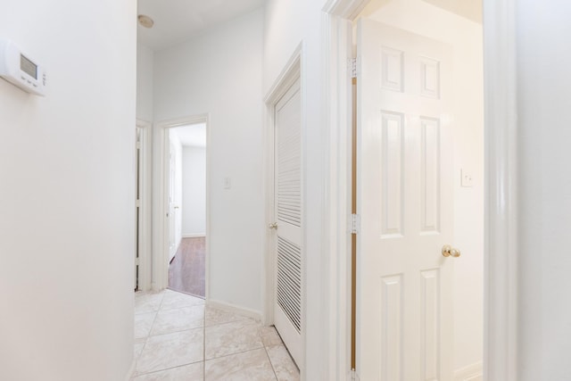 corridor featuring baseboards and light tile patterned floors