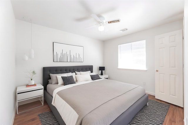 bedroom featuring visible vents, ceiling fan, baseboards, and wood finished floors