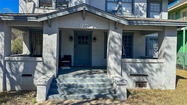 doorway to property featuring covered porch and stucco siding