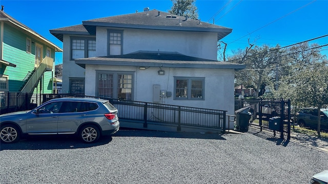 view of front of property featuring a fenced front yard, roof with shingles, and stucco siding