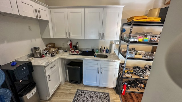 kitchen with light stone counters, white cabinets, and a sink