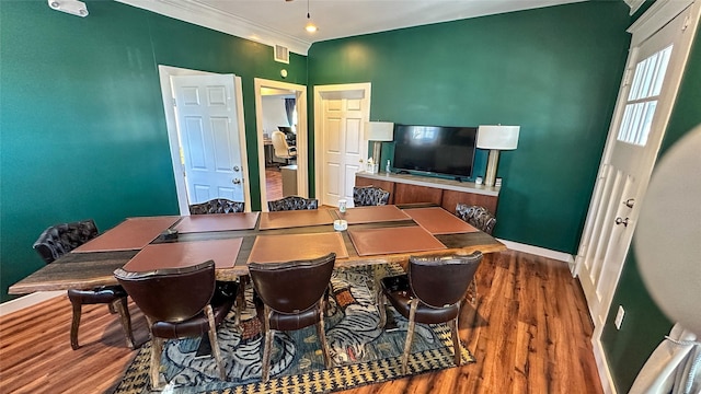 dining space featuring baseboards, visible vents, ornamental molding, and wood finished floors