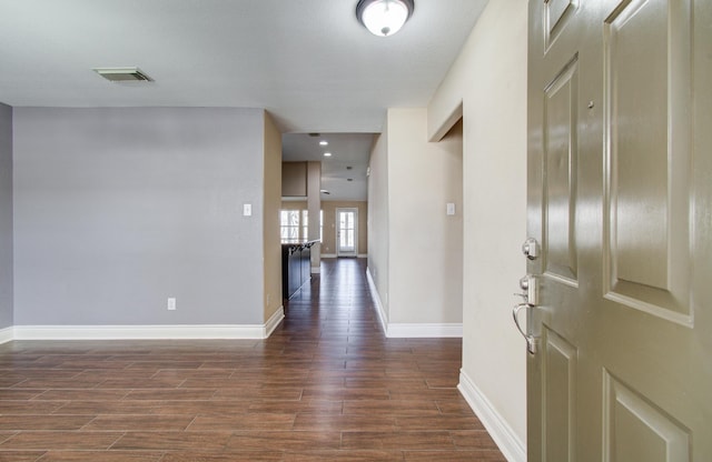 foyer entrance with baseboards, visible vents, and dark wood-type flooring