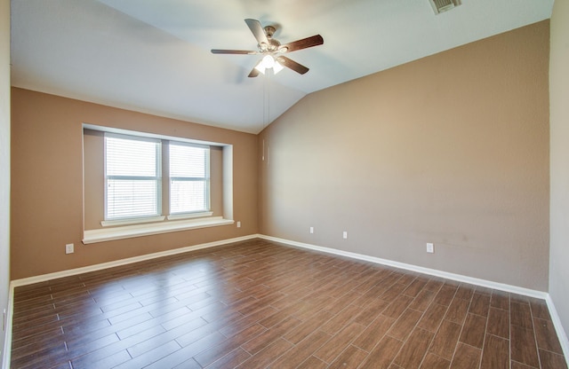 empty room featuring lofted ceiling, baseboards, dark wood finished floors, and a ceiling fan