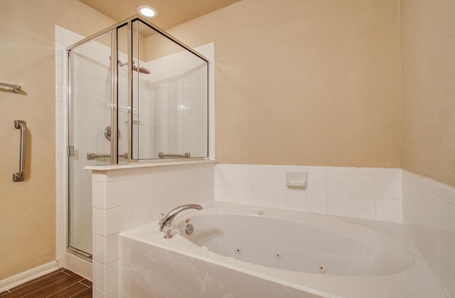 bathroom with a stall shower, a jetted tub, baseboards, and wood finished floors