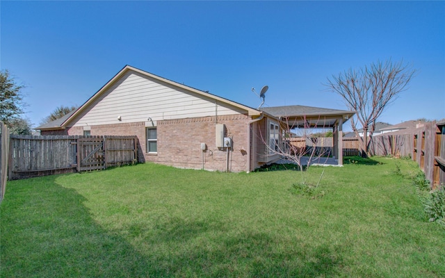 back of property featuring brick siding, a yard, and a fenced backyard