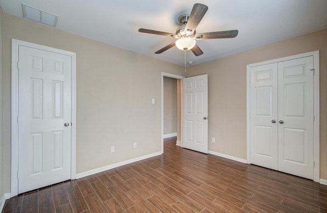 unfurnished bedroom with a closet, visible vents, a ceiling fan, wood finished floors, and baseboards