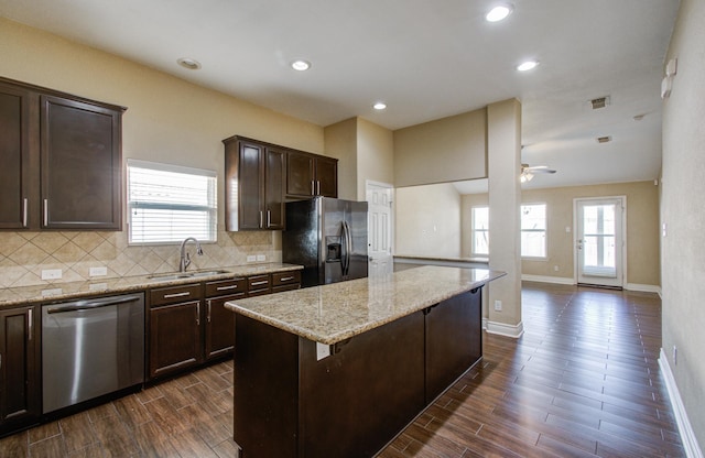 kitchen featuring black fridge with ice dispenser, a center island, dark brown cabinets, stainless steel dishwasher, and a sink