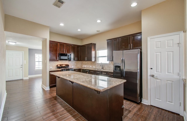 kitchen with a kitchen island, a sink, gas range, black microwave, and stainless steel fridge with ice dispenser