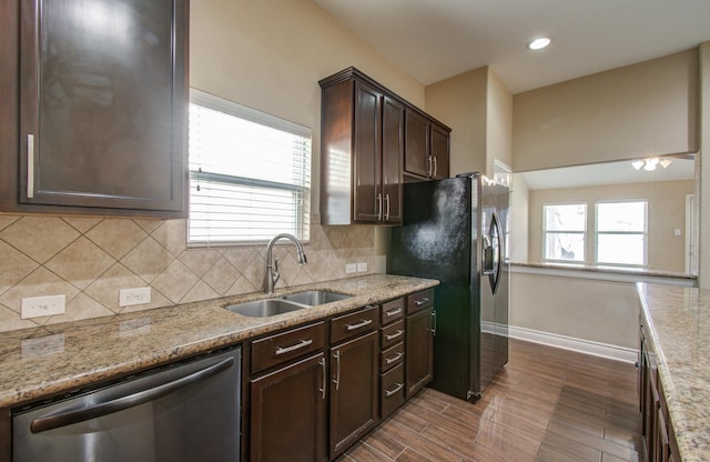 kitchen with stainless steel appliances, tasteful backsplash, a healthy amount of sunlight, a sink, and dark brown cabinets