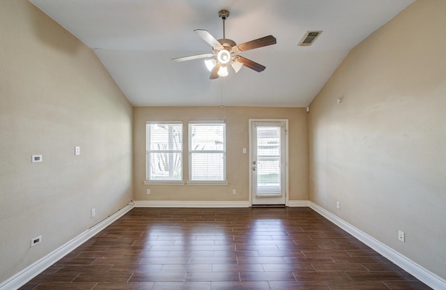 empty room featuring baseboards, visible vents, dark wood finished floors, a ceiling fan, and lofted ceiling