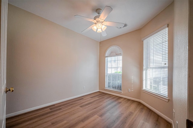 spare room with visible vents, baseboards, wood finished floors, and a ceiling fan