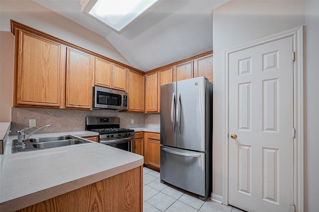 kitchen with light tile patterned flooring, a sink, decorative backsplash, light countertops, and appliances with stainless steel finishes