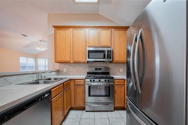 kitchen featuring light tile patterned flooring, vaulted ceiling, stainless steel appliances, and a sink