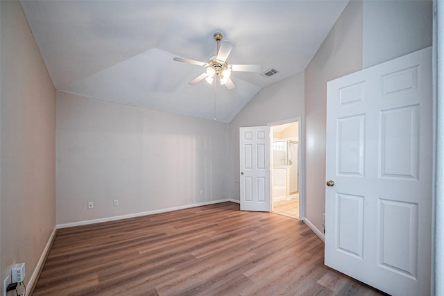 unfurnished bedroom with wood finished floors, visible vents, baseboards, ensuite bath, and vaulted ceiling