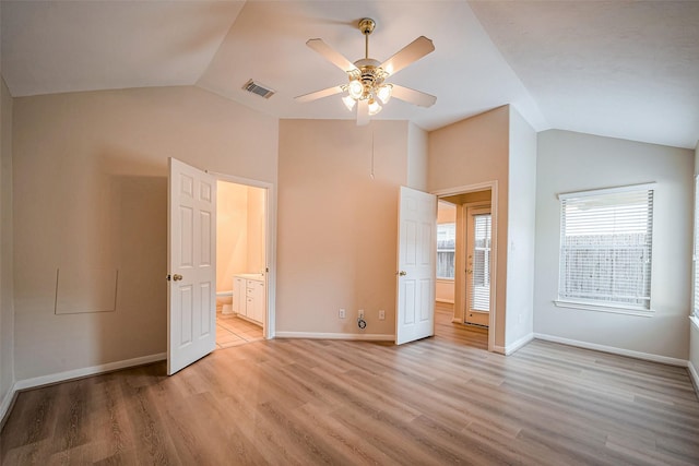 unfurnished bedroom featuring light wood finished floors, visible vents, connected bathroom, baseboards, and vaulted ceiling