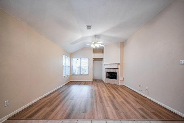 unfurnished living room featuring visible vents, a tile fireplace, light wood finished floors, ceiling fan, and vaulted ceiling