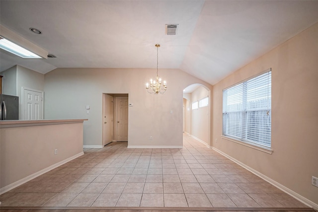 empty room featuring visible vents, lofted ceiling, light tile patterned flooring, arched walkways, and a notable chandelier