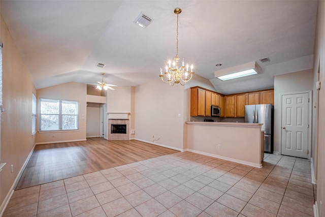 kitchen with visible vents, ceiling fan with notable chandelier, stainless steel appliances, light tile patterned floors, and lofted ceiling