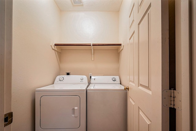 washroom featuring a textured ceiling, laundry area, visible vents, and washer and clothes dryer