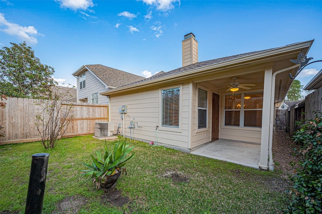 rear view of house with ceiling fan, central air condition unit, a lawn, a fenced backyard, and a patio