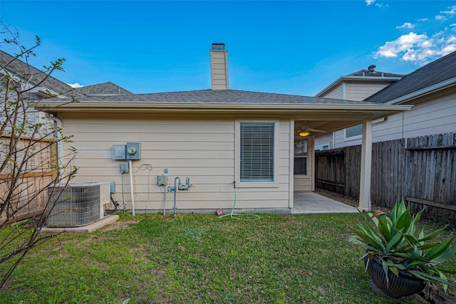 rear view of property with ceiling fan, a lawn, cooling unit, a fenced backyard, and a patio